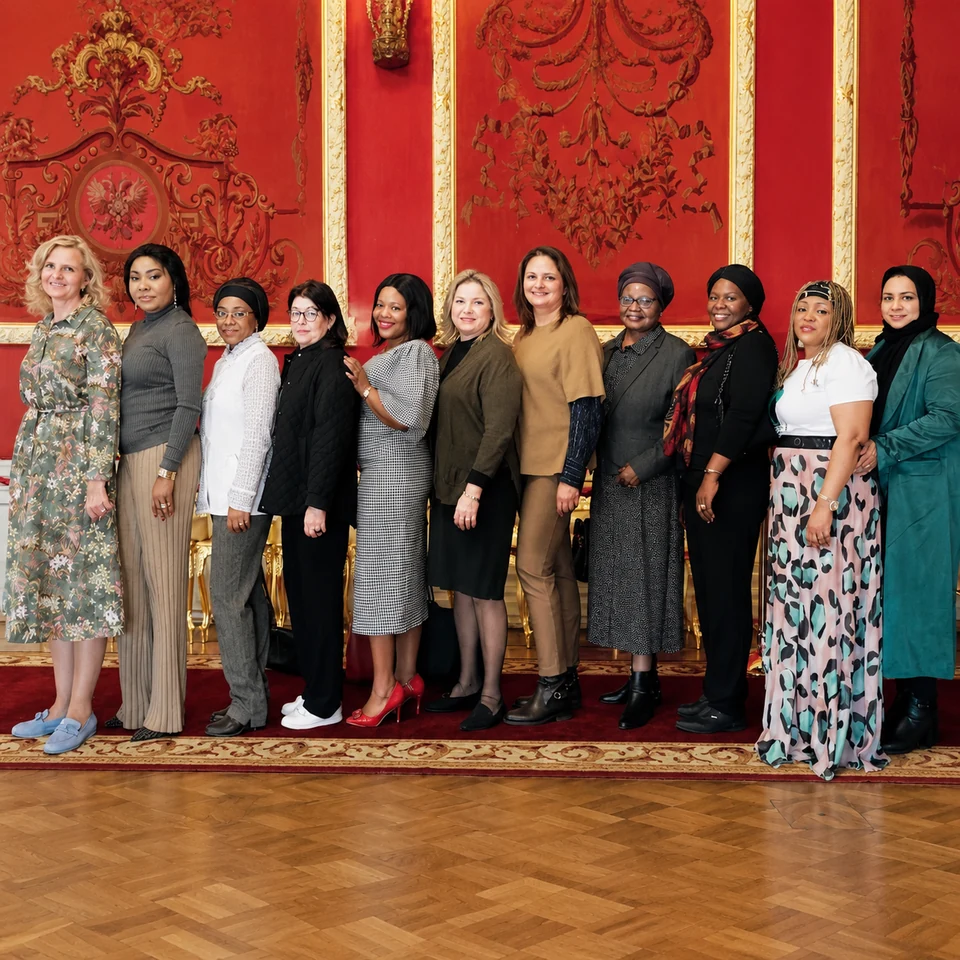 Photo de groupe des participantes dans une salle aux panneaux rouges et dorés